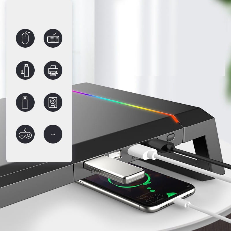 Support de moniteur RGB avec station d’accueil USB et tiroir de rangement en noir, doté d’un éclairage RGB et de plusieurs ports USB pour charger des appareils sur un bureau de jeu.
