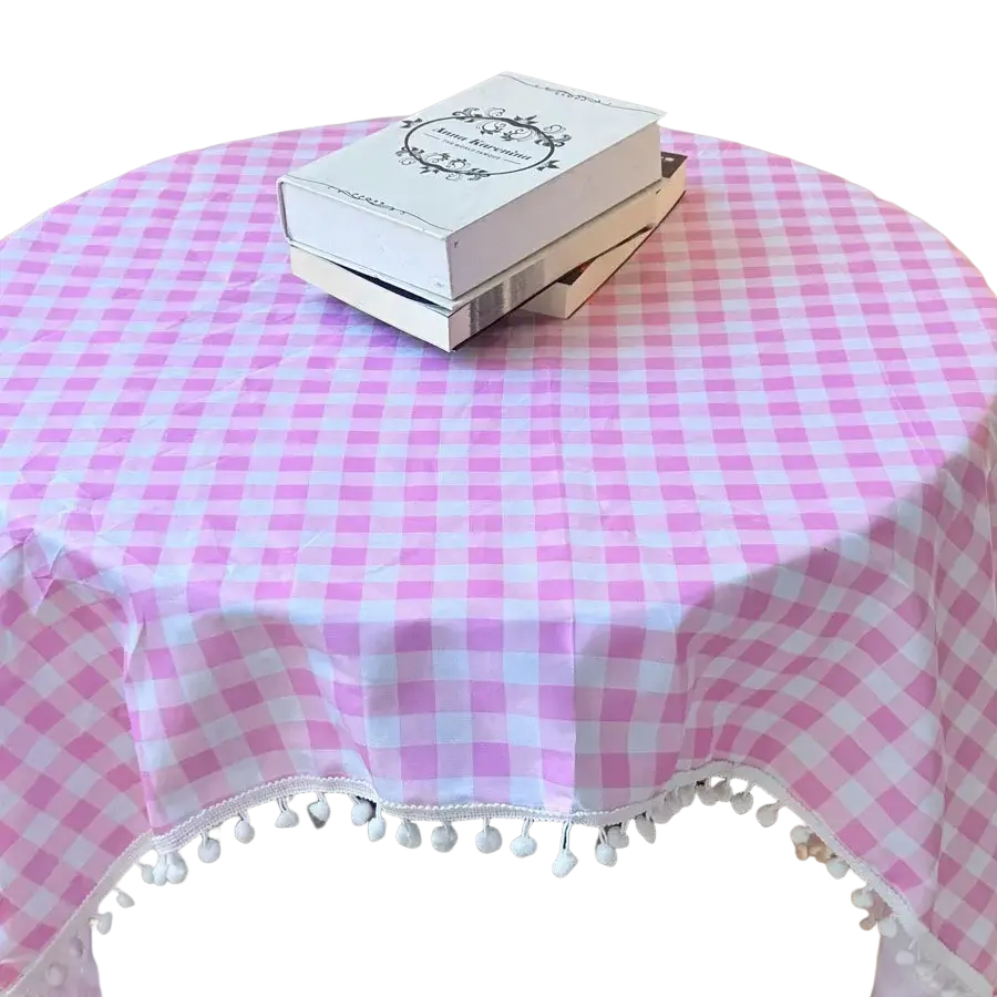 Mantelería con ribete de encaje de lunares rosa que presenta un patrón de cuadros tipo gingham rosa y blanco con ribete decorativo de pompón, mostrada desde un ángulo cenital.