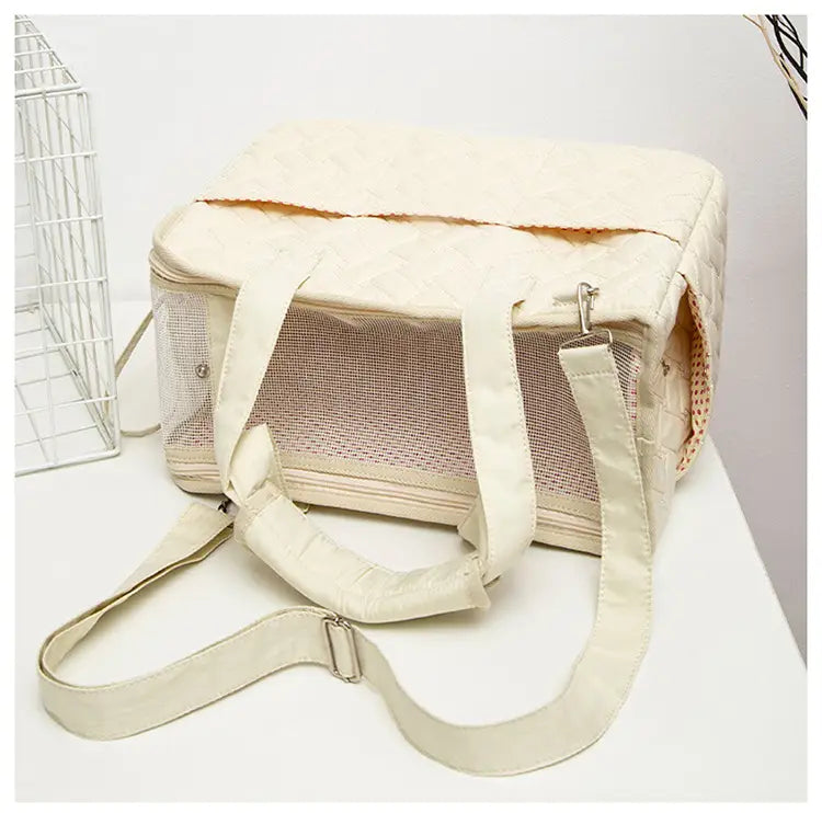 Sac pour animal de compagnie matelassé de couleur crème, avec des côtés en maille respirante et des poignées rembourrées, conçu pour les petits porte-chiens.