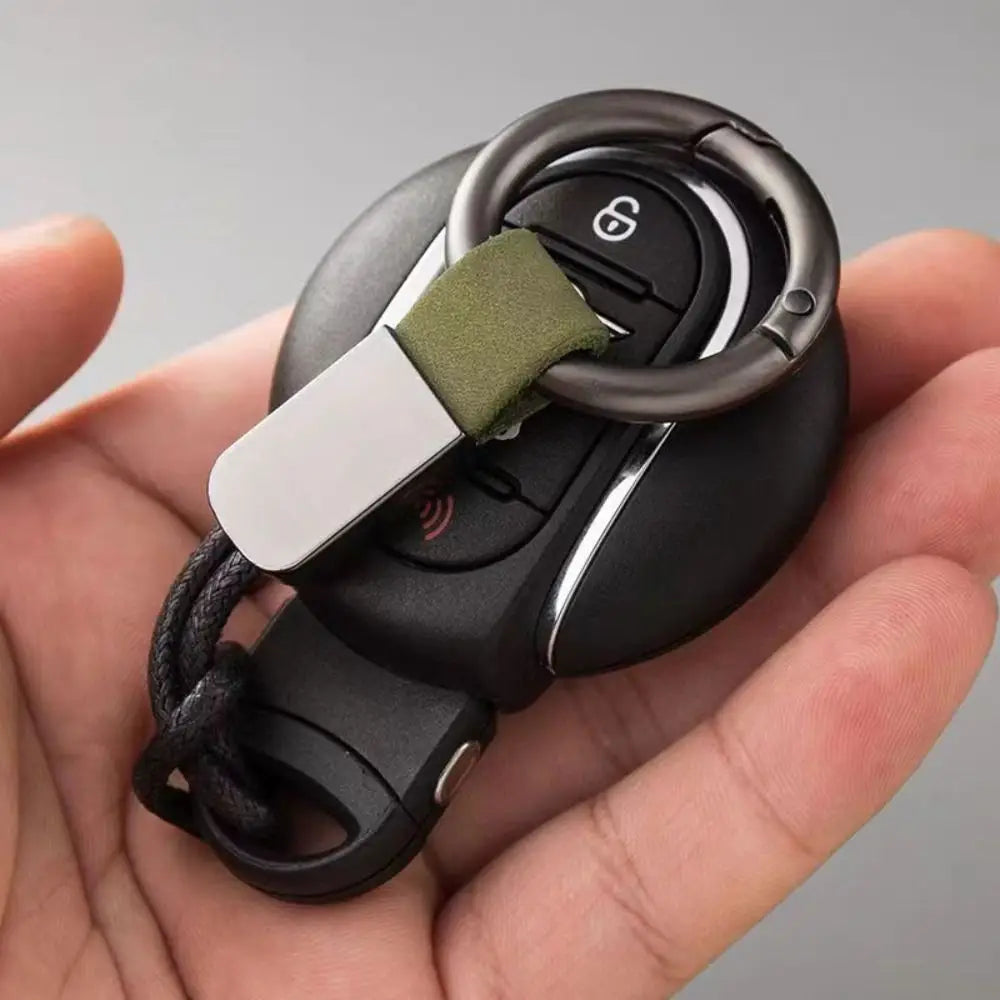 Black car key fob attached to a silver metal ring and olive green leather strap on a leather carabinieri keychain anti lost business key holder.
