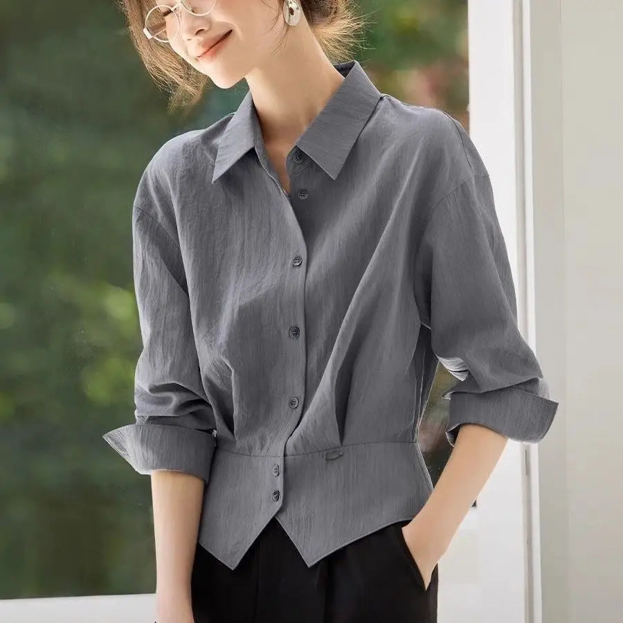 Chemise manches longues en lin grise pour femmes, manches retroussées et taille cintrée, conçue comme une blouse de bureau ajustée.