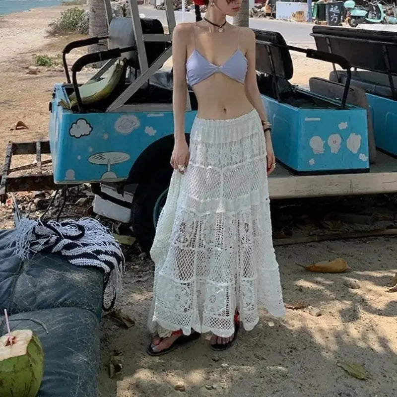 A flowing white crochet maxi skirt with tiered layers and delicate lace detailing ideal for summer wear.