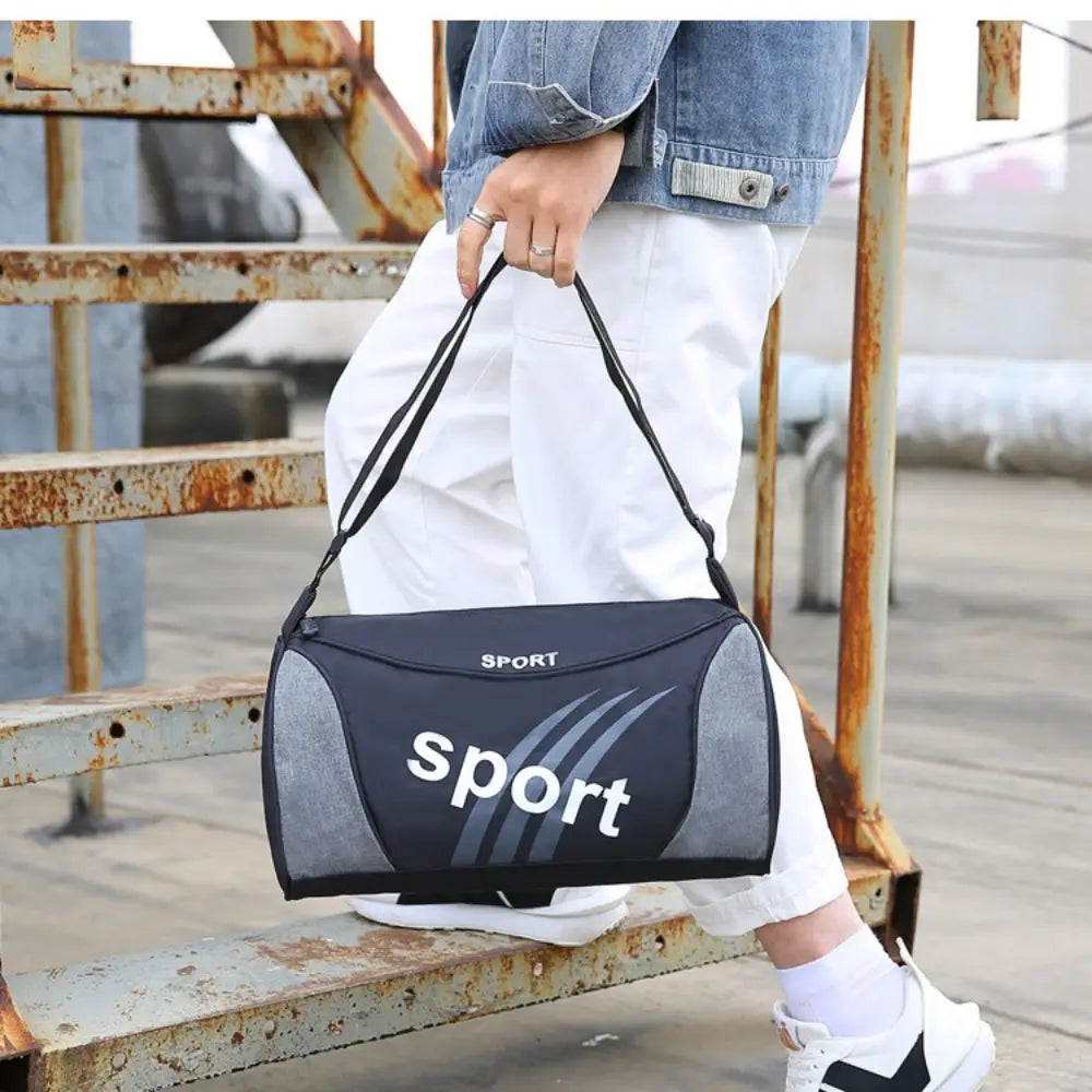 Petit sac de gym pour l’entraînement de remise en forme sportive, sac duffel à porter en bandoulière, en noir et gris, avec inscriptions sportives blanches et rayures diagonales.