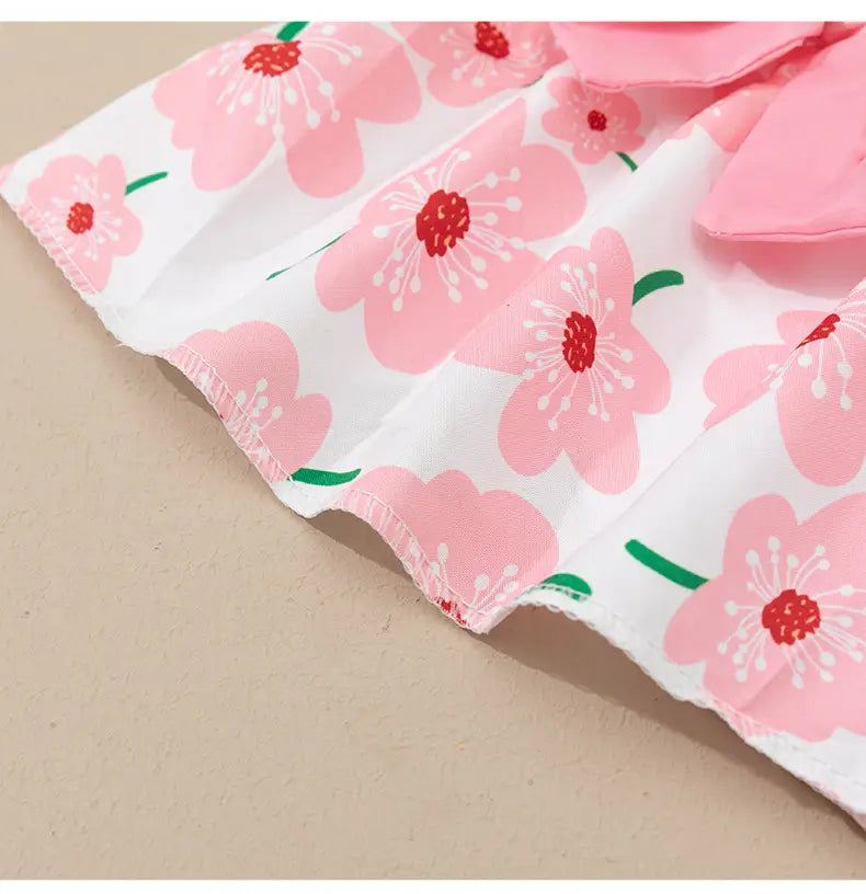 Floral dog princess dress with bow featuring a white fabric with pink floral pattern green stems and ruffled edges.