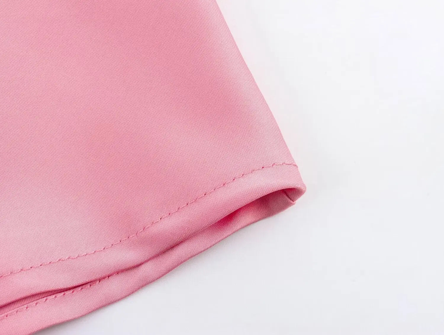 Une jupe midi en satin rose tendre, à taille haute, bords cousus avec précision et confectionnée dans un tissu lisse, légèrement réfléchissant pour une allure élégante.