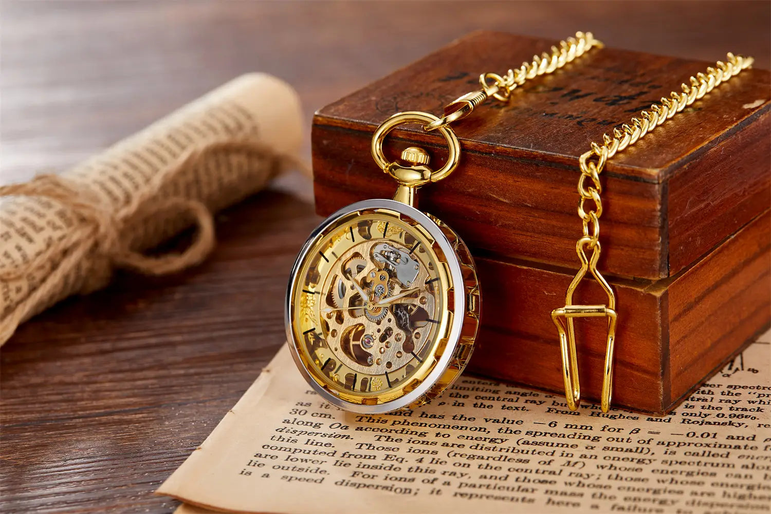 Montre de poche mécanique en or, squelette à remontage par la main, avec engrenages à tonalité or apparents et lunette à tonalité argent posée sur un livre ouvert.