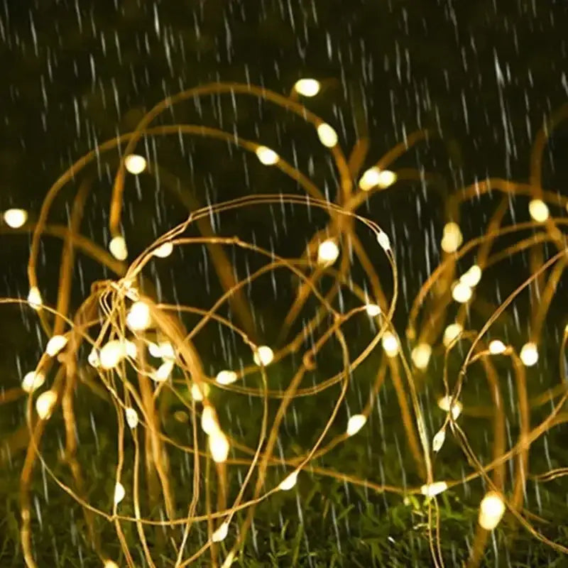 guirlande de lumières solaires pour extérieur à DEL blanc chaud avec petites ampoules sphériques sur un fin fil de cuivre, affichée sous un angle frontal rapproché