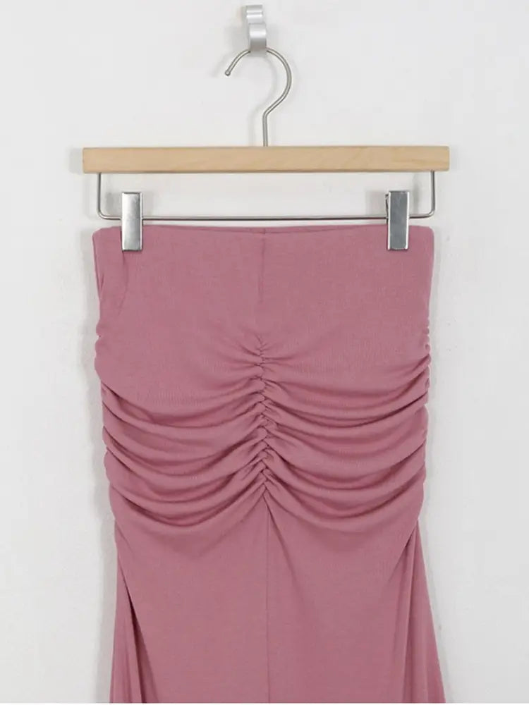 Ein zartes rosafarbenes, gerafftes ärmelloses Midirock-Modell mit hoher Taille im Meerjungfrauen-Stil, das an einem Holzkleiderbügel hängt.