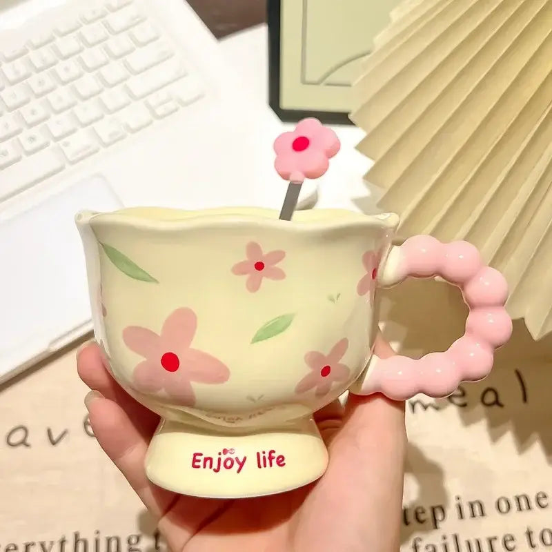 Tasse tulipe en céramique jaune pastel avec des décors floraux roses et une anse assortie en perles, portant l’inscription « enjoy life » sur sa base, dans une boîte cadeau à motif floral.