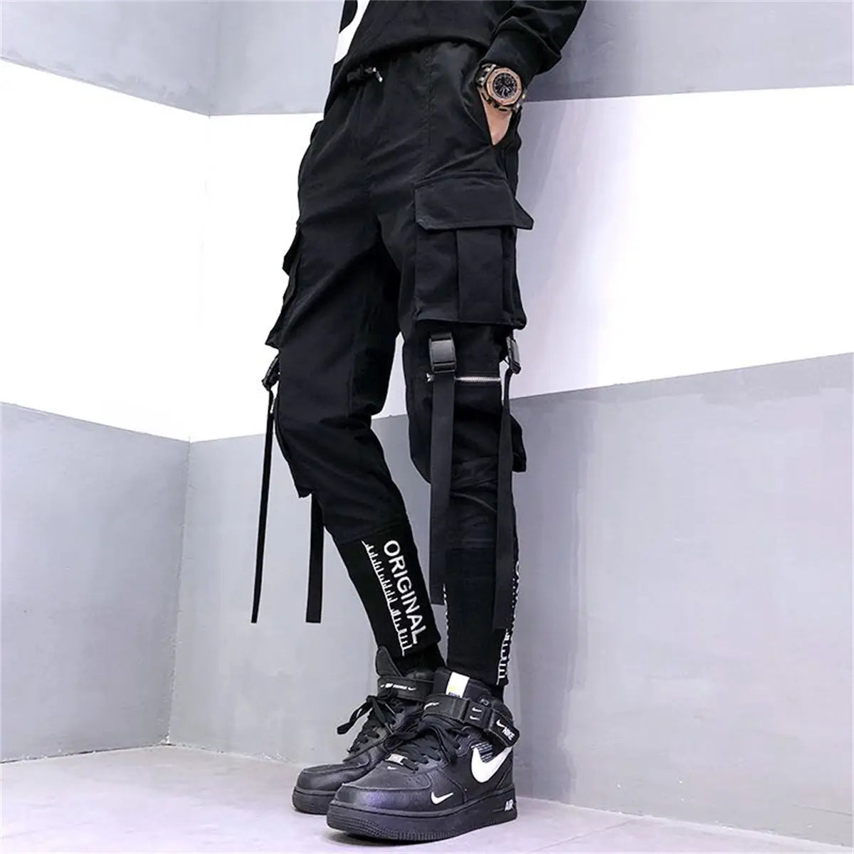 Pantalons cargo tactiques pour hommes noirs, dotés de plusieurs poches, de sangles réglables et de lettrage original blanc le long du côté, conçus pour le techwear et le streetwear.