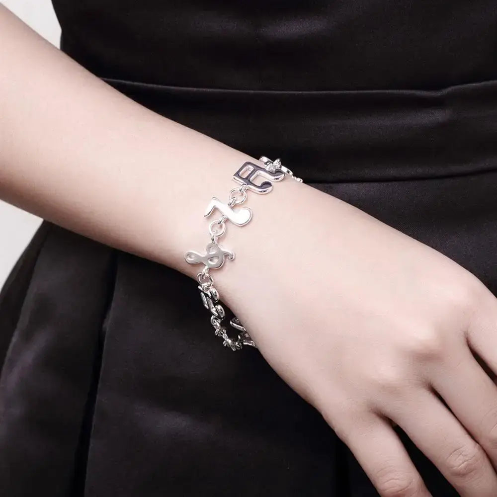 Silver musical note sterling silver bracelet featuring delicate chain links and sparkling accents.