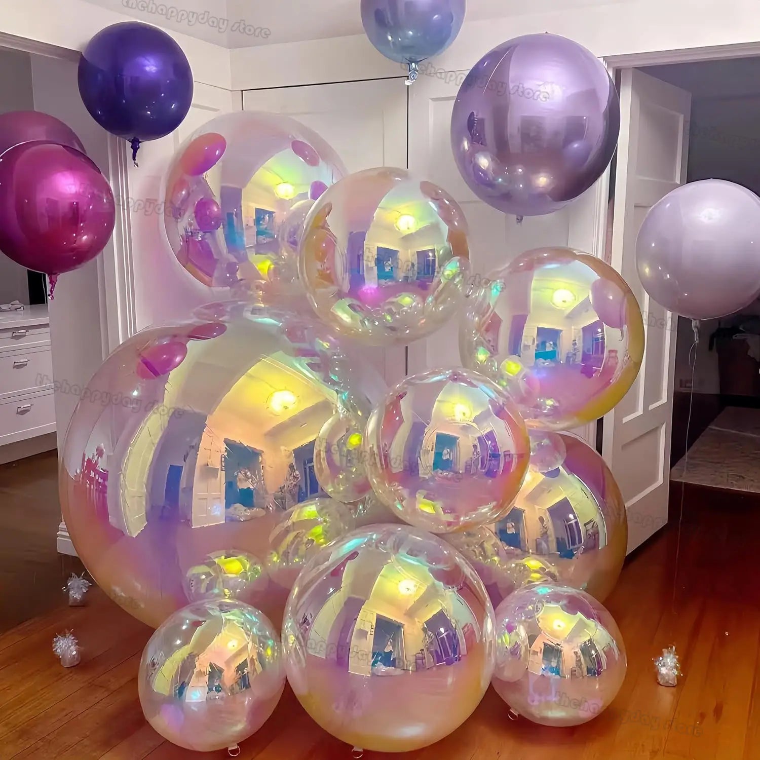 un ensemble de ballons réfléchissants irisés aux nuances de violet et de rose, accompagnant une pancarte de bienvenue personnalisée pour baby shower ronde sur panneau KT, présentée à l’intérieur.