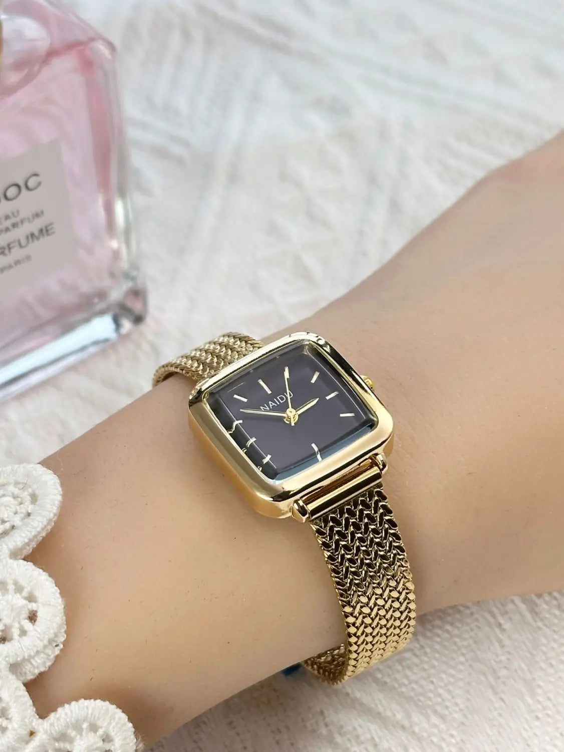 Minimalist square quartz watch for women featuring a gold-toned square face with a black dial and a gold mesh band.
