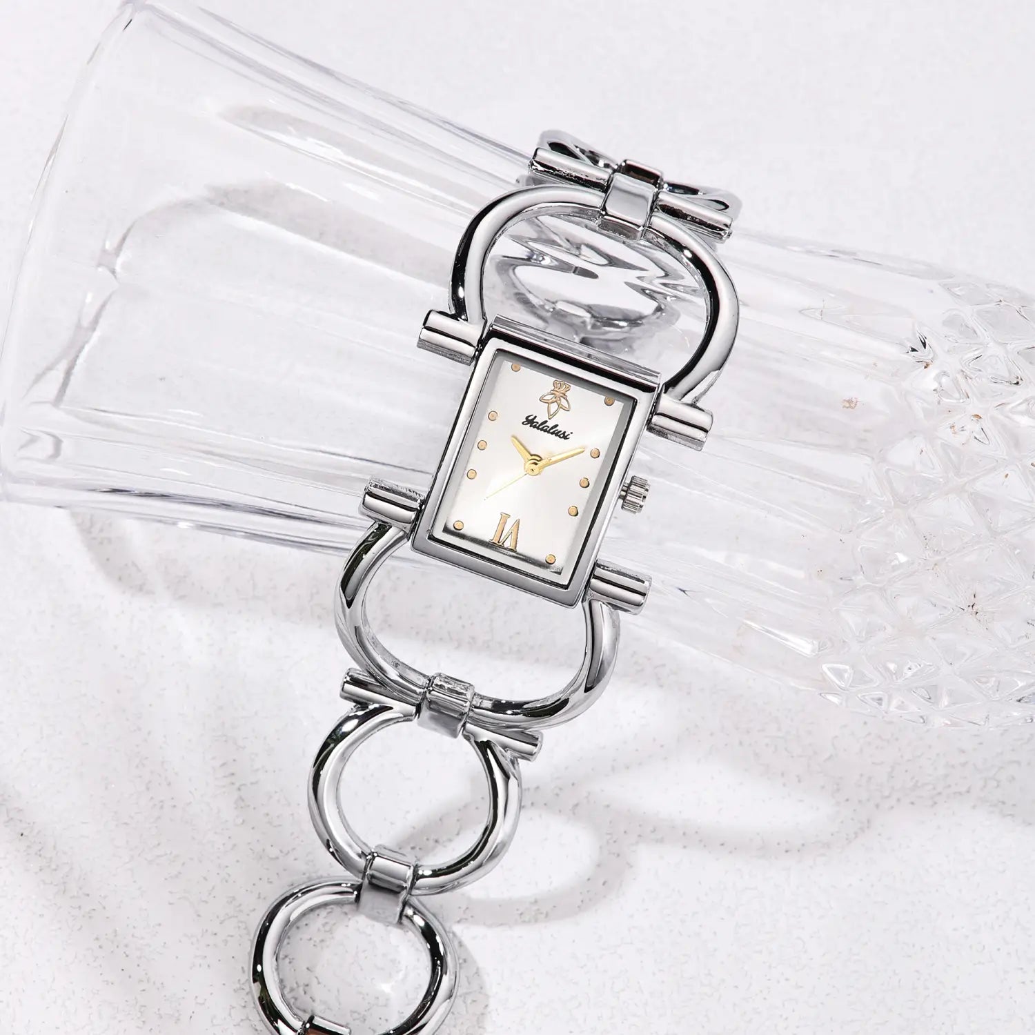Silver-toned gold luxury quartz women watch bracelet with a rectangular face, pearl-like dial, gold-tone hands and hour markers, featuring an ornate link bracelet design.