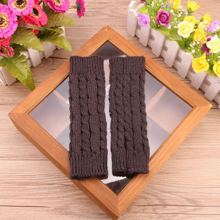 Dunkelbraune, gestrickte fingerlose Handschuhe mit Zopfmuster, dargestellt auf einem mit Holzrahmen versehenen Spiegel; für Frauen entworfen; gestrickte fingerlose Handschuhe mit Zopfmuster als Winterstulpen.