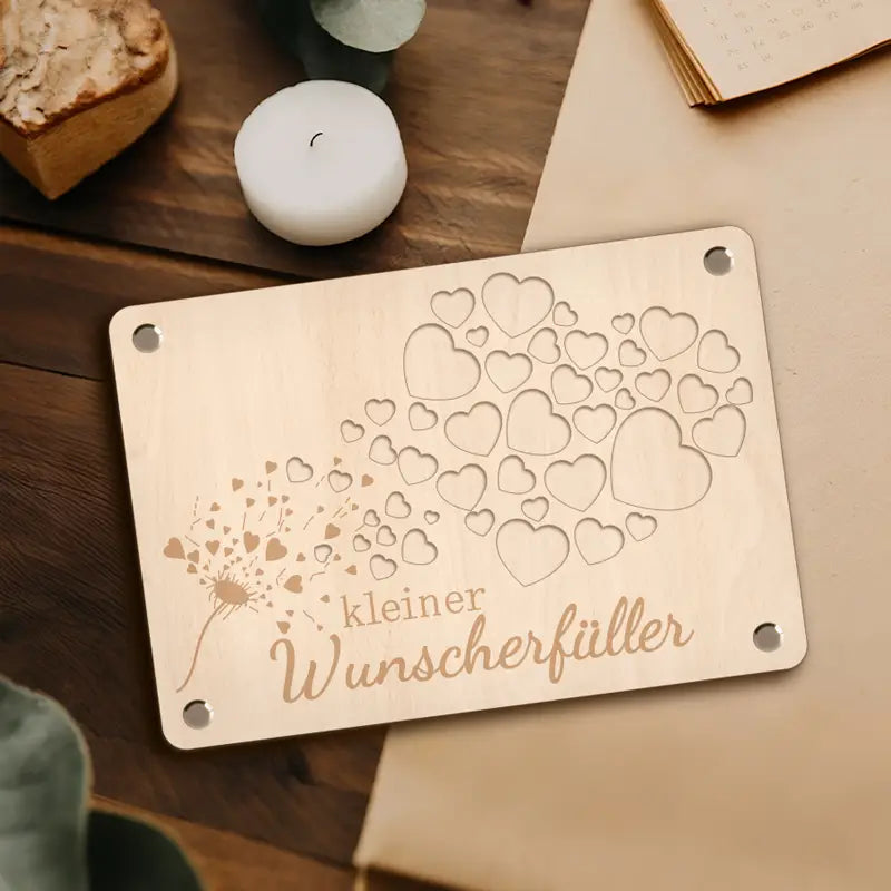 ハートが吹き飛ぶタンポポの彫刻デザインと、その下にドイツ語の「kleiner wunscherfüller」が記された淡い色の木製マネーギフトカード用プラーク。