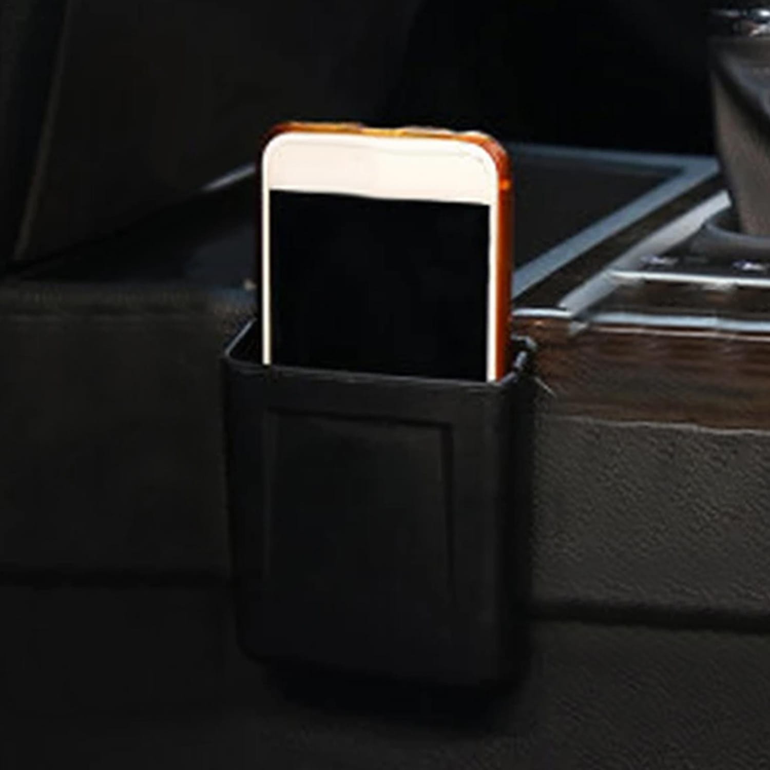 Organizador de almacenamiento para coche de cuero negro de montaje en bolsillo del tablero ABS, con un teléfono inteligente blanco en una funda naranja colocado en el interior.