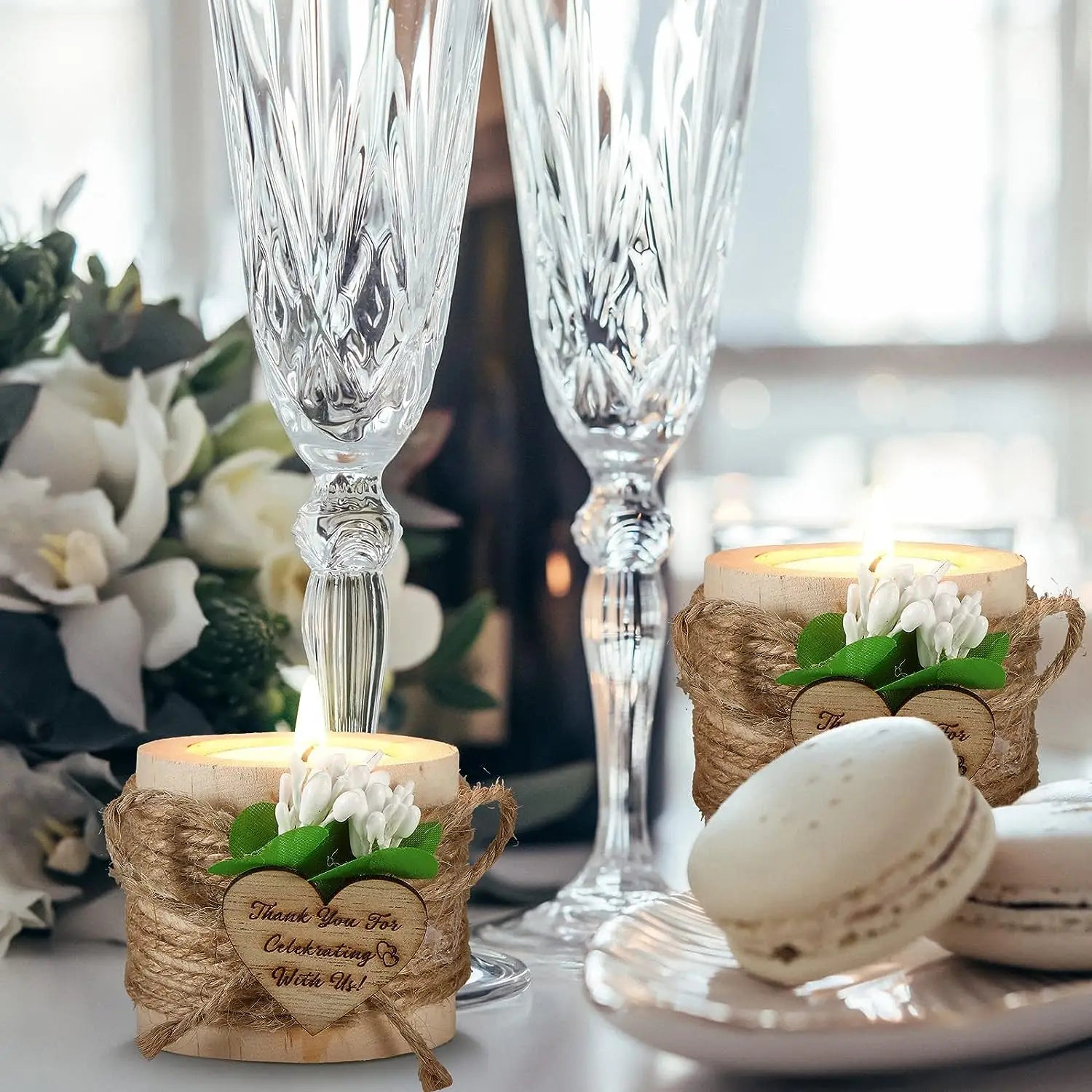 Des flûtes à champagne en cristal transparent, finement découpées, avec une tige et un bol facettés, accompagnées de bougeoirs en bois pour petites bougies chauffe-plat, comme cadeaux d’invités de mariage, avec une finition naturelle.