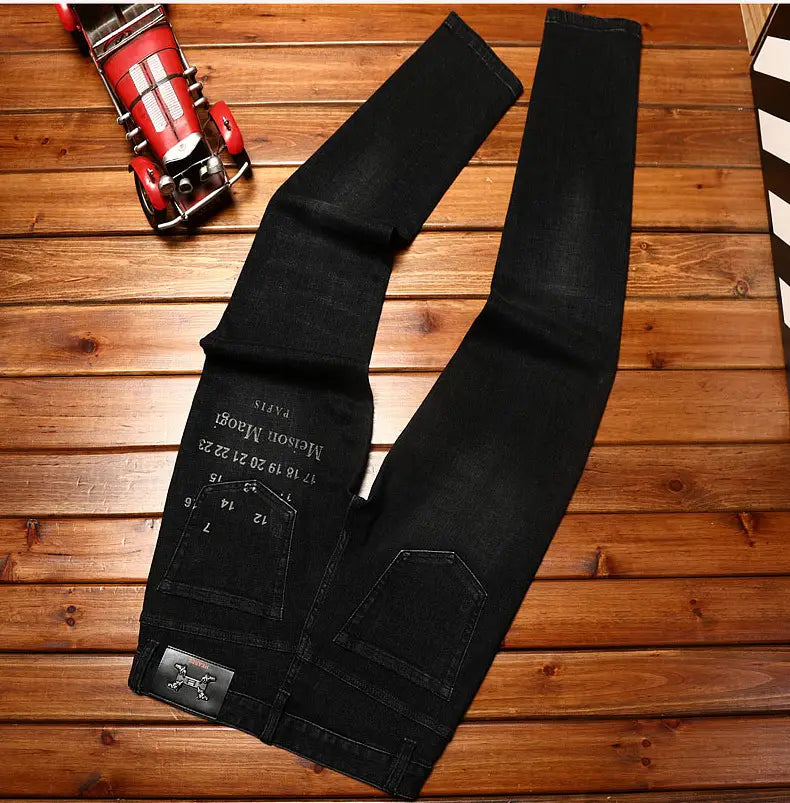 mens slim fit printed black denim jeans shown from the back side featuring faded wash, black denim material, a branded patch on the back pocket, and a metallic tag at the waistband.