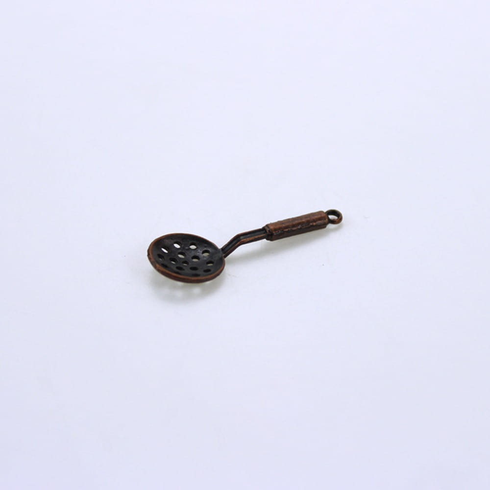 Breloque de cuillère miniature à fente de couleur bronze antique, avec manche détaillé et perforations circulaires, provenant d’un ensemble d’ustensiles de cuisine miniature pour maison de poupée.
