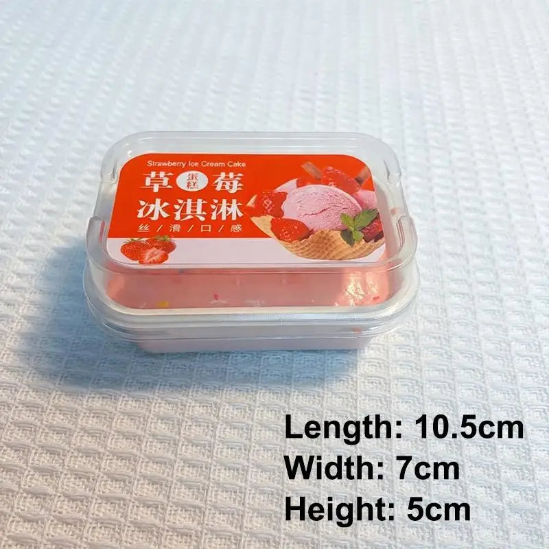 un recipiente de plástico transparente que contiene un pastel simulado de helado de color rosa, con una etiqueta roja y blanca que muestra una imagen del postre, diseñado como un juguete sensorial tipo fidget de crecimiento lento