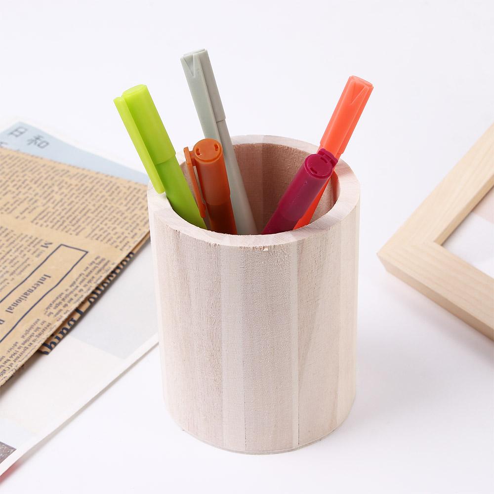 Porte-stylo cylindrique en bois de couleur claire, à rainures verticales, utilisé comme boîte de rangement pour organisateur de bureau, contenant des marqueurs colorés.