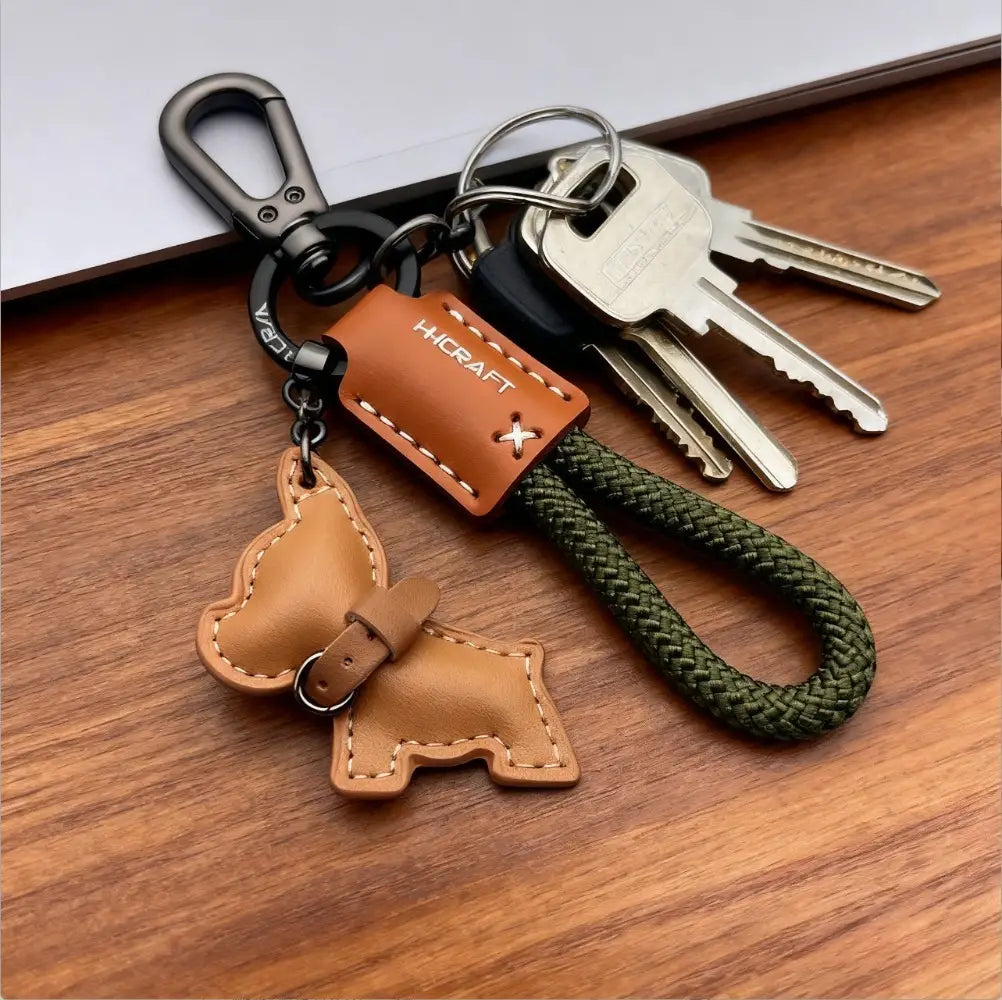 French bulldog leather keychain in tan with stitched details and a braided olive green cord.