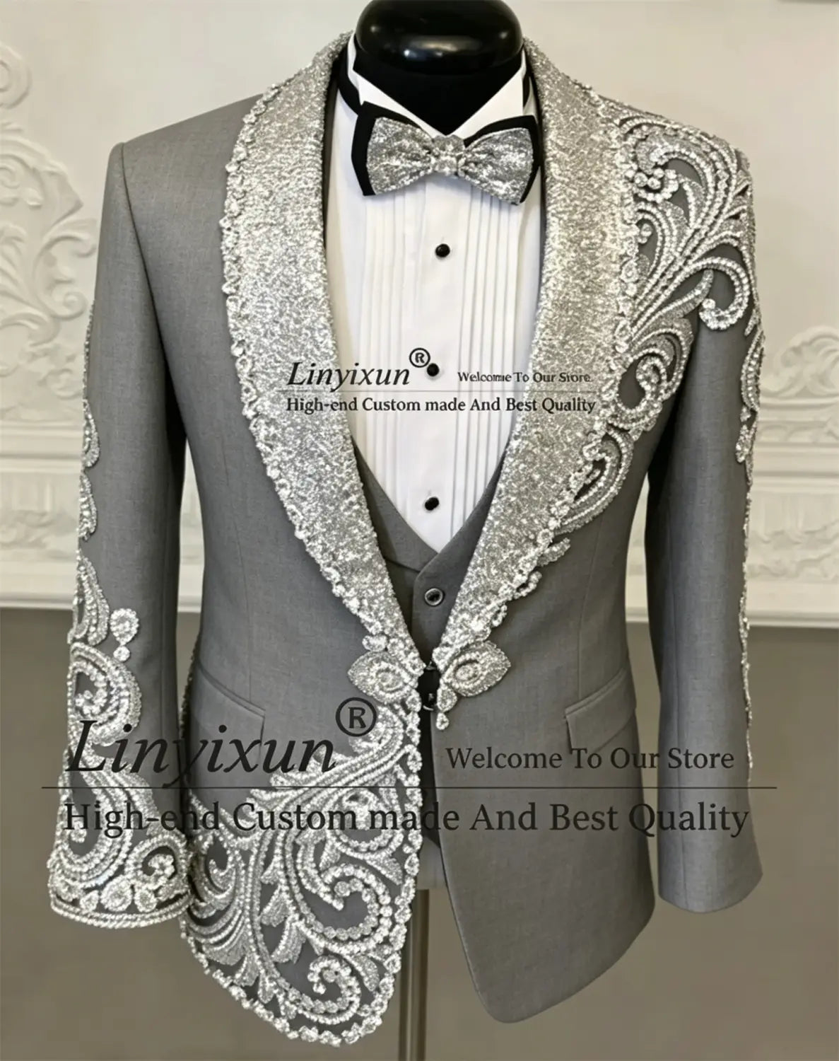 Costume de tuxedo de mariage pour hommes en velours noir, avec une veste grise rehaussée d’argent, présentant des détails complexes de perles et de sequins sur les revers, les épaules et les poignets.