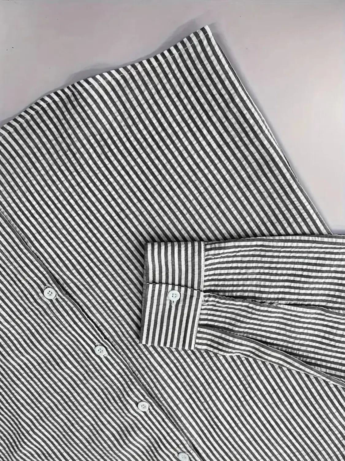 Chemise décontractée boutonnée manches longues à rayures bleues pour homme, réalisée dans un coton noir et blanc à rayures nettes, avec col classique et poignets soigneusement pliés.