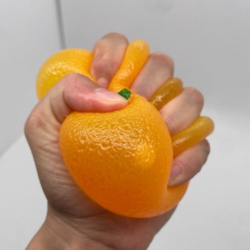 Jouet sensoriel d’anti-stress en silicone orange façonné comme un agrume orange vif, avec une peau texturée et un détail de tige verte.