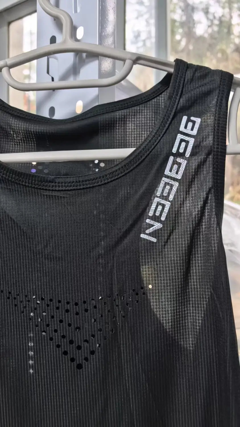 Chaleco para correr de hombre de malla negra que incorpora material transpirable de secado rápido, con letras Gegeen blancas y pequeñas perforaciones a lo largo de la parte frontal.
