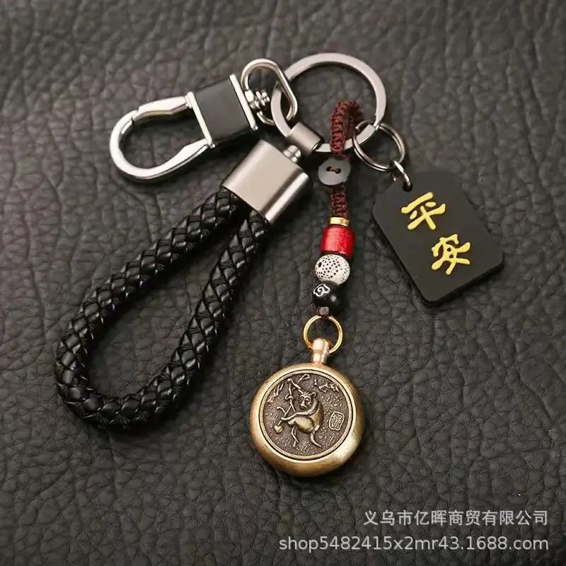 中国の干支ラッキーペンダントのコレクション用。刻印デザインのブロンズ円形ペンダントと、金色の漢字が記された黒いタグを備えた黒の編みレザー製キーチェーン。