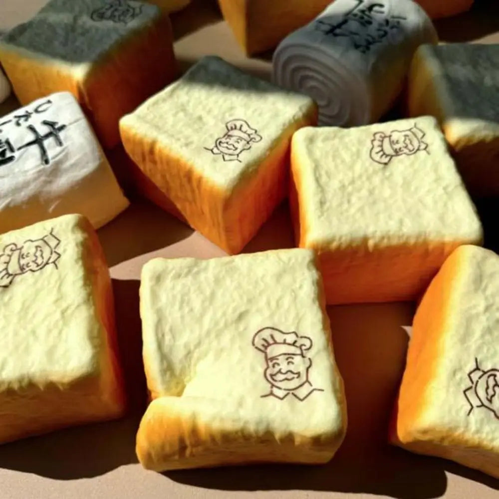 golden-brown square chef bread squishy toy with soft porous texture and black chef illustrations on top viewed from the front as a fidget toy for universal age range