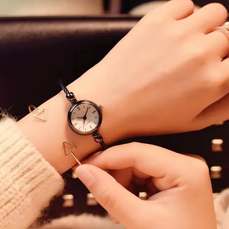 Women stainless steel quartz bangle watch featuring a black braided bracelet with a white face and roman numerals.