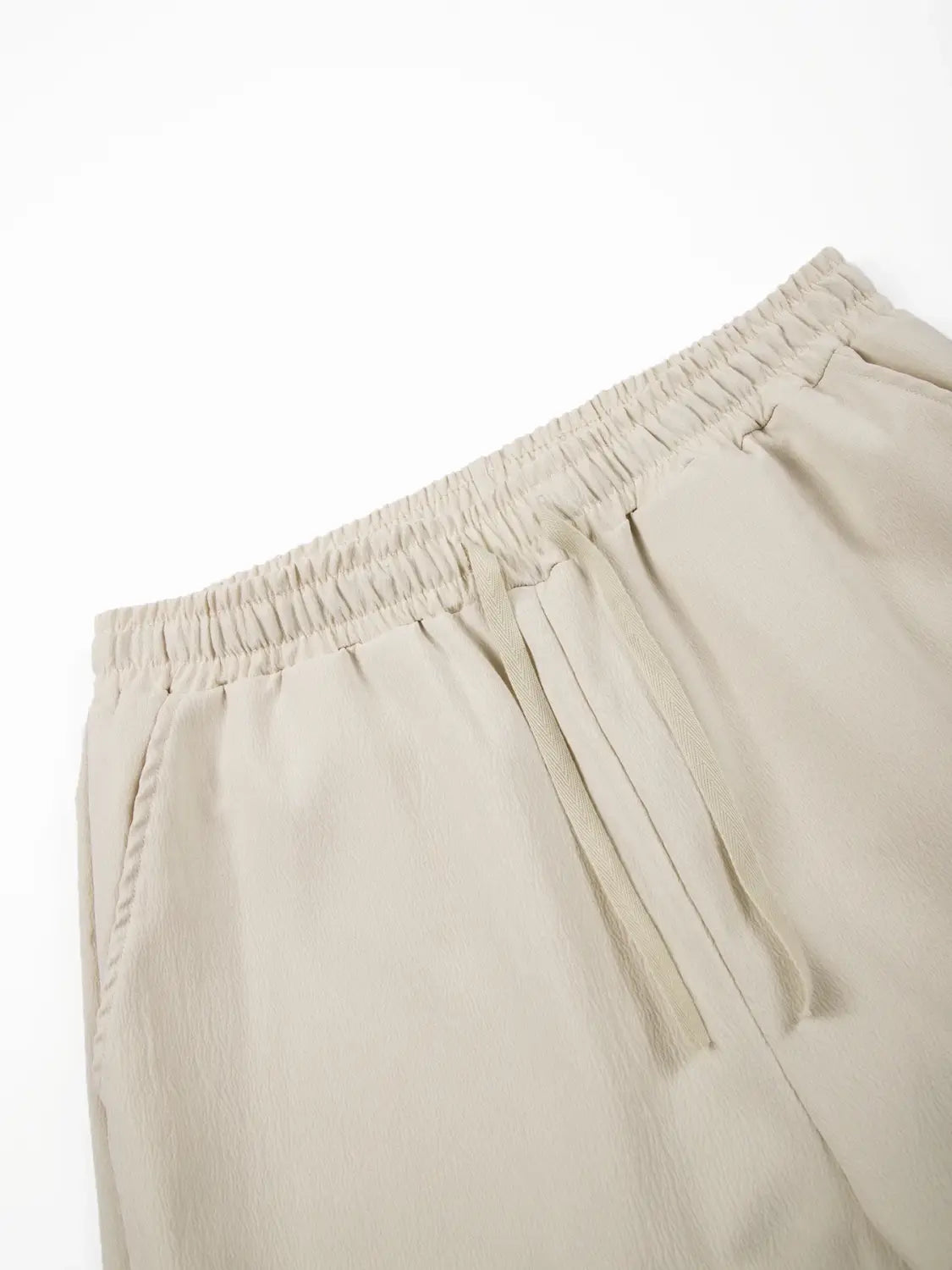 Beige Leinenhosen mit elastischem Bund, entspannter leichter Stoff und dezente Details an den Seitennahtverläufen aus dem Herren-Leinen-Zweiteiler für den Sommer.