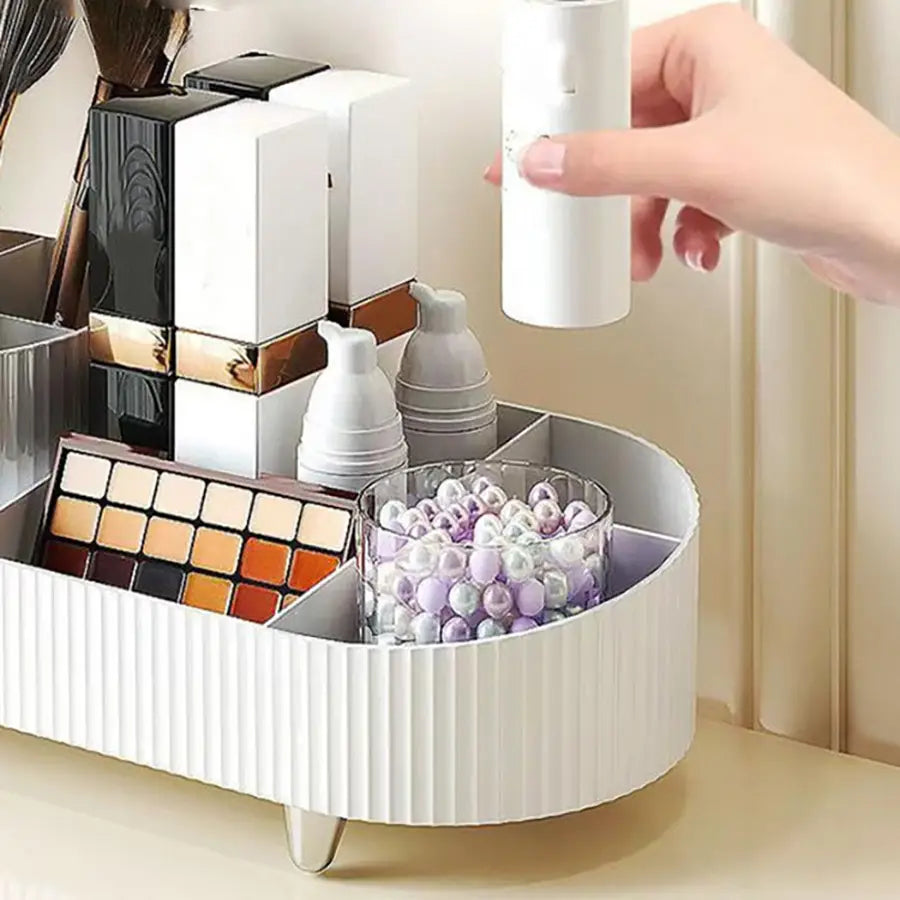 Weißer gerippter Kunststoff-Dreh-Make-up-Organizer, Kosmetik-Display-Gehäuse mit mehreren Fächern und einer modernen Stil-Aufbewahrungsbox, die Kosmetika und eine Glasschale mit dekorativen Perlen enthält.