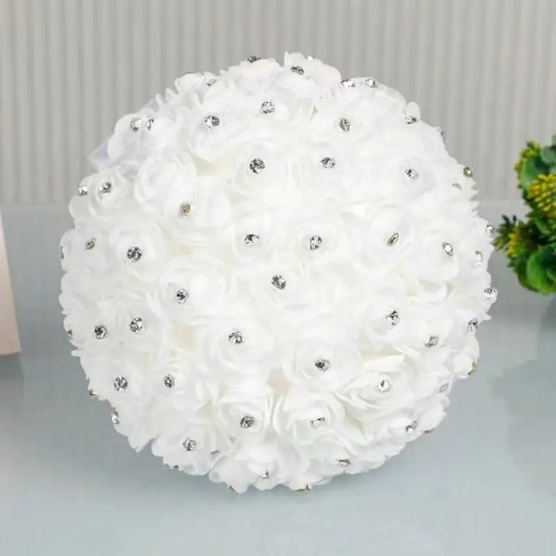 きらめくシルバーのラインストーンをあしらった、白い布製の花による球状のアレンジメントを特徴とするラインストーンの結婚指輪リングピローのフローラル・ブライダルブーケ。