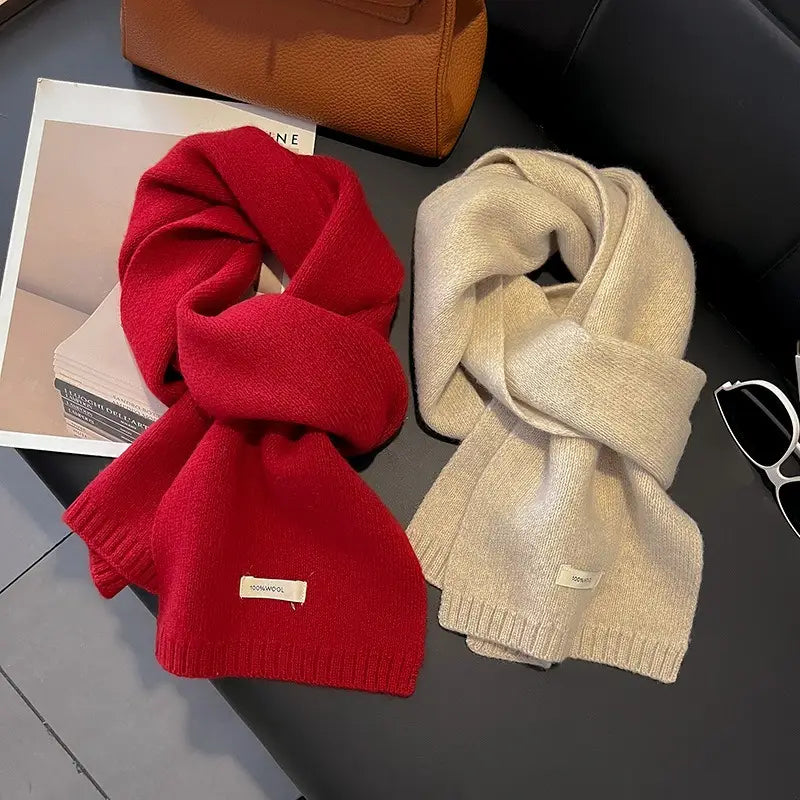 Una bufanda de invierno roja y beige tejida, acogedora, para hombres y mujeres, con bordes acanalados y una pequeña etiqueta de marca.