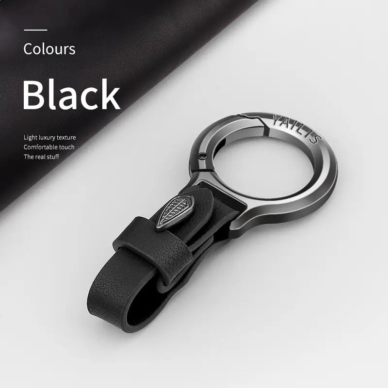 Black leather car keychain with metallic ring and embossed logo featuring a leaf charm.