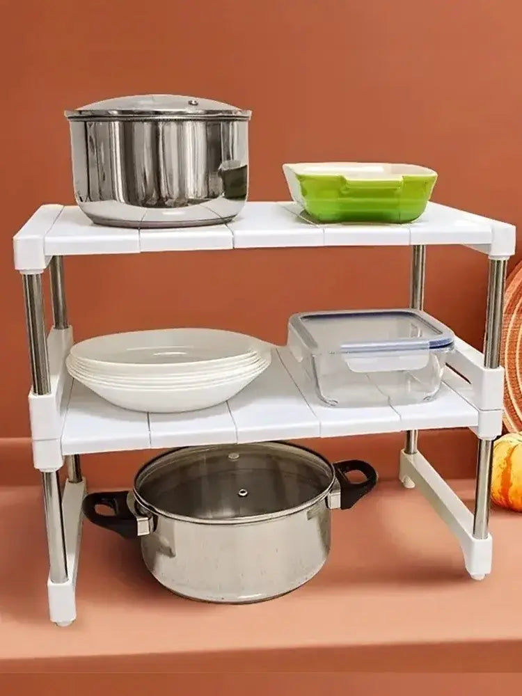 White two-tiered telescopic sink holder layered partition rack with chrome metal legs and plastic shelves for kitchen organization.