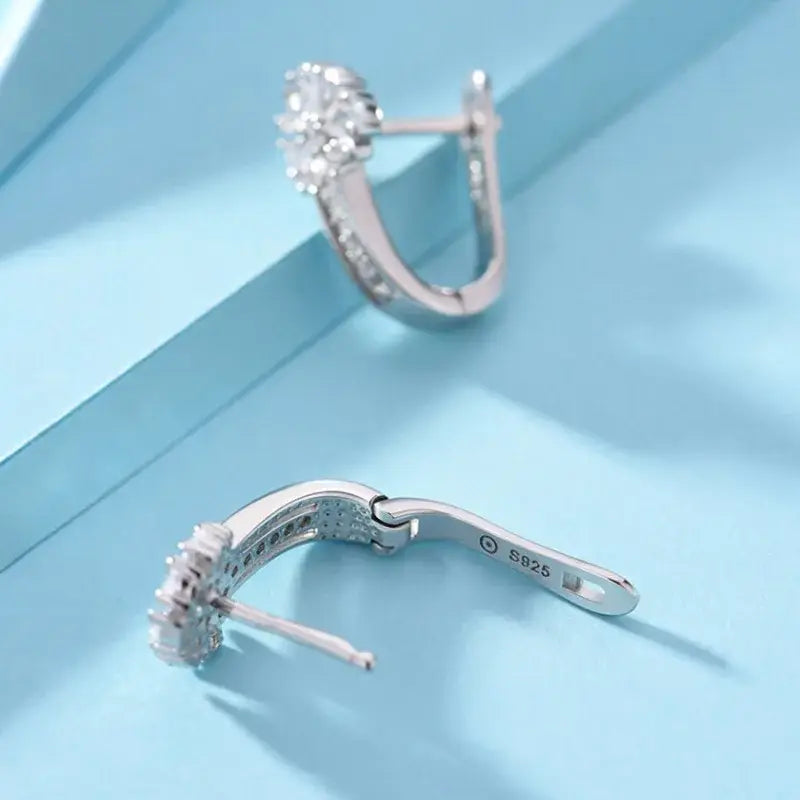 Pendientes de flores de circonio en plata de ley con diseño de tipo huggie de plata, adornado con piedras transparentes que brillan y un acabado elegante y esbelto.