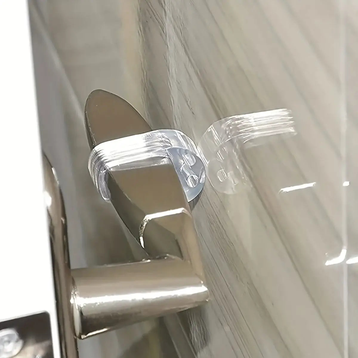 Pare-chocs mural pour poignée de porte, muni d’une protection en plastique clair au design flexible, enveloppant une poignée métallique.