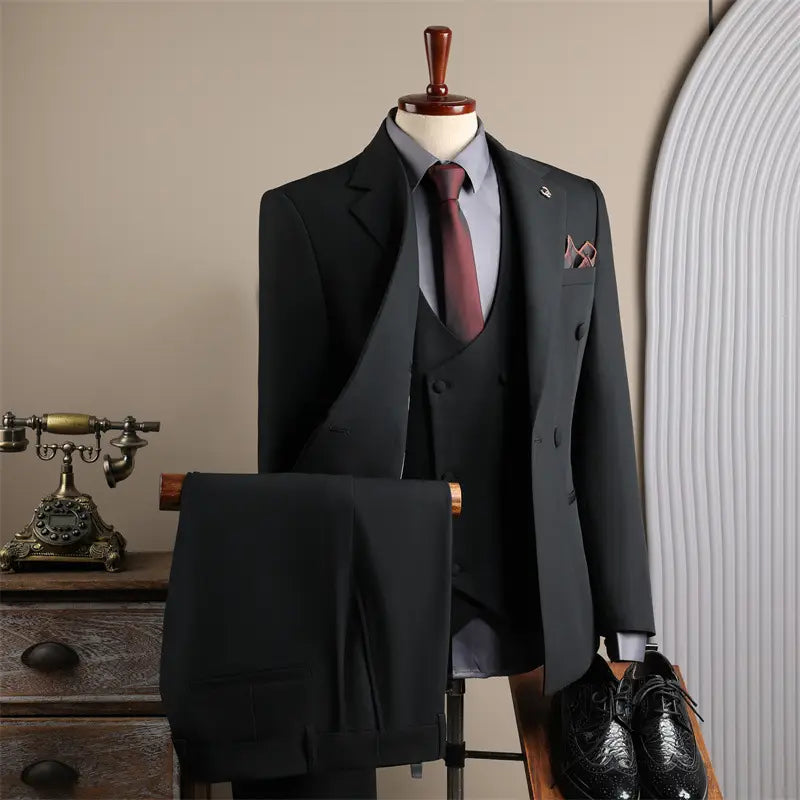 Costume d’affaires pour homme slim fit trois pièces noir, avec pantalon assorti et cravate bordeaux présentée sur un mannequin, adapté à la mode masculine, aux affaires et aux soirées décontractées.