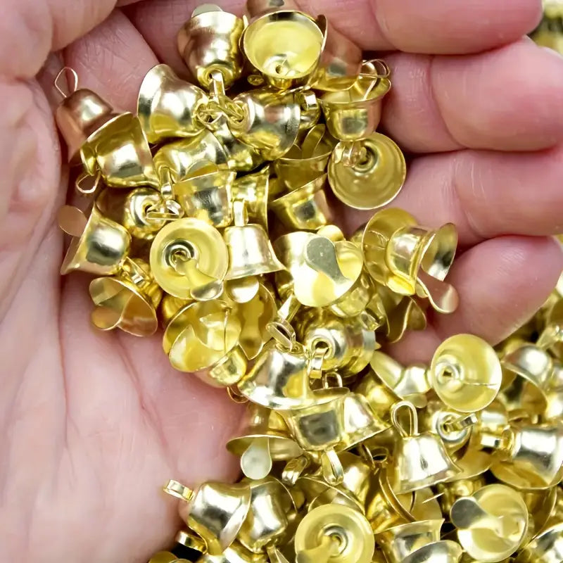 Un ensemble de 20 petites clochettes de traîneau en métal doré brillant, avec des sommets bouclés et des intérieurs creux.
