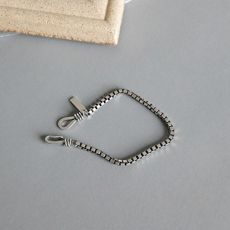 L’image présente un bracelet de charme en métal géométrique ton argent pour couples, doté d’un design minimaliste et élégant, avec des maillons de chaîne à boîte polis.