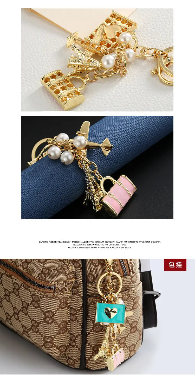Llavero de viaje en tono dorado con colgantes de avión, perlas y maleta rosa, diseñados como accesorio de bolso.