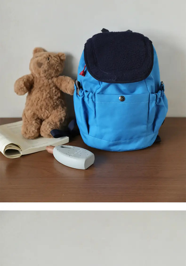 Leuchtend blauer leichter Fuzzy-Rucksack für Kinder mit dunkelblauer oberer Klappe und verstellbaren Seitenriemen, geeignet für die Verwendung als Kindergartentagesrucksack.