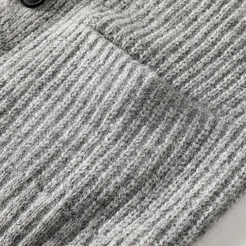 Detailaufnahme eines weichen grauen Herren-V-Ausschnitt-Strickcardigans aus strukturiertem geripptem Strick mit sichtbaren Fasern und leichten Farbtonunterschieden.