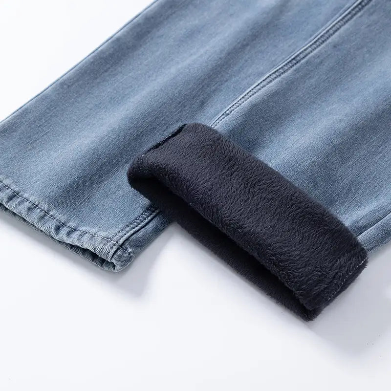 Jeans rétro délavés coupe droite ample pour hommes en denim clair, avec une doublure en molleton gris foncé souple visible au niveau du revers retroussé.