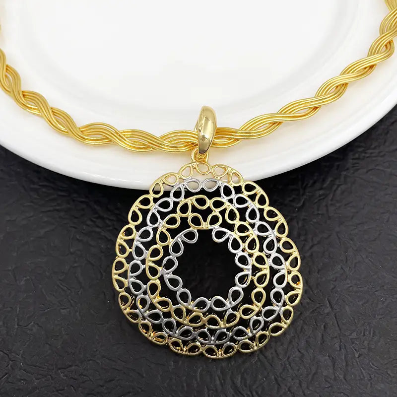 Pendentif en filigrane bicolore or et argent présentant un motif goutte complexe, issu d’un ensemble de bijoux pour femmes.